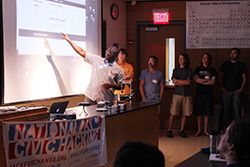 Gyepi Sam explains the team's code to the Hack for Western Mass participants at the end of the weekend. 